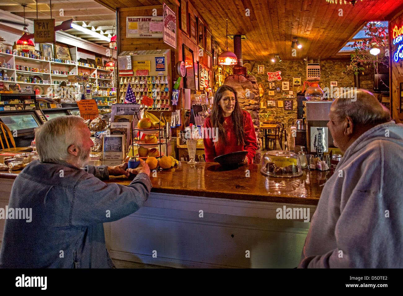 Der Inhaber einer altmodischen Gemischtwarenladen plaudert mit zwei ihrer Kunden an der Snackbar im Vulkan, CA. Stockfoto