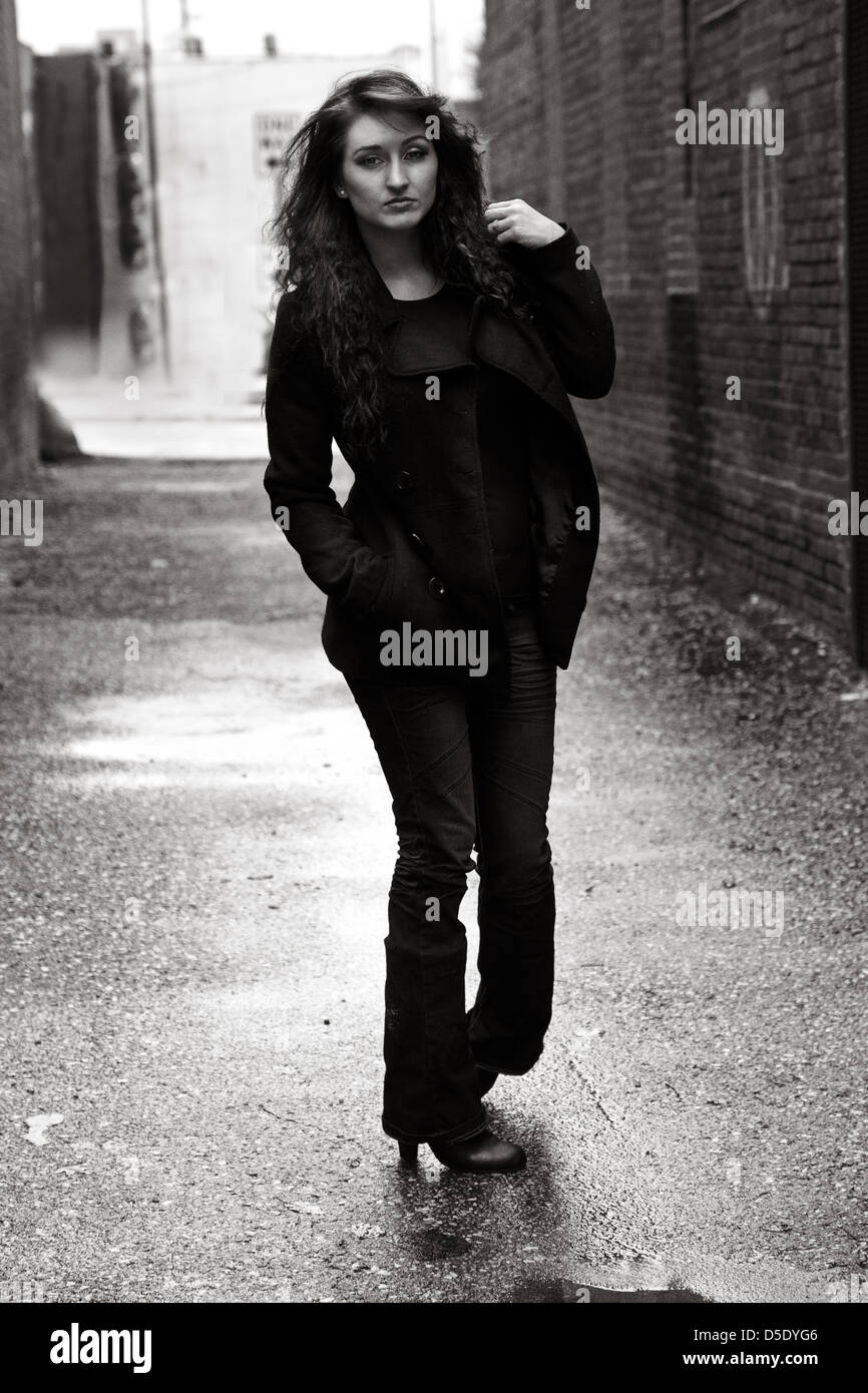 Frau im Dunkel gekleidet gehen durch Regen durchnässt Gasse Stockfoto