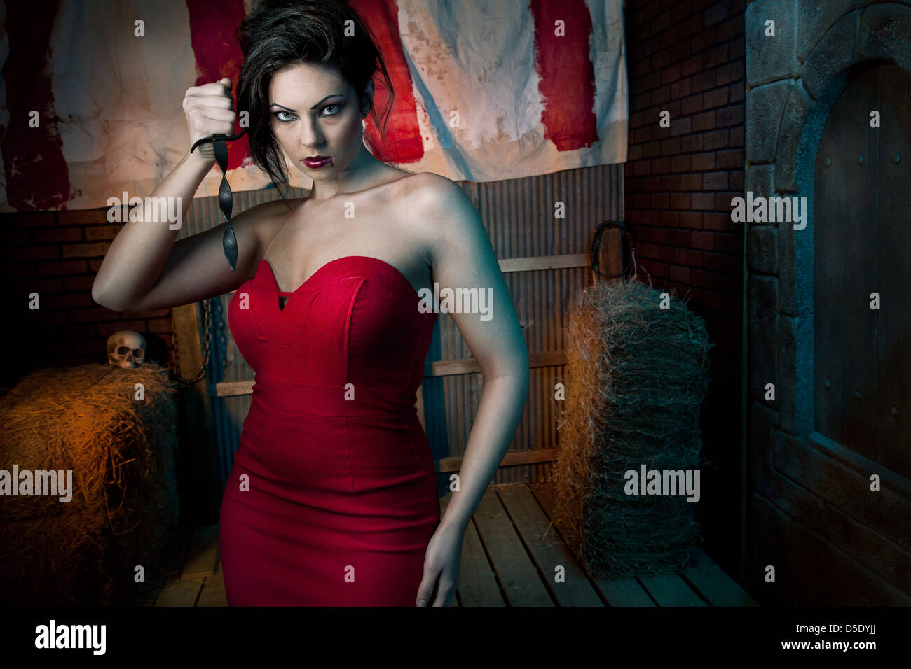 Frau mit Dolch im roten Kleid vor dunklen Zelt Gasse Stockfoto