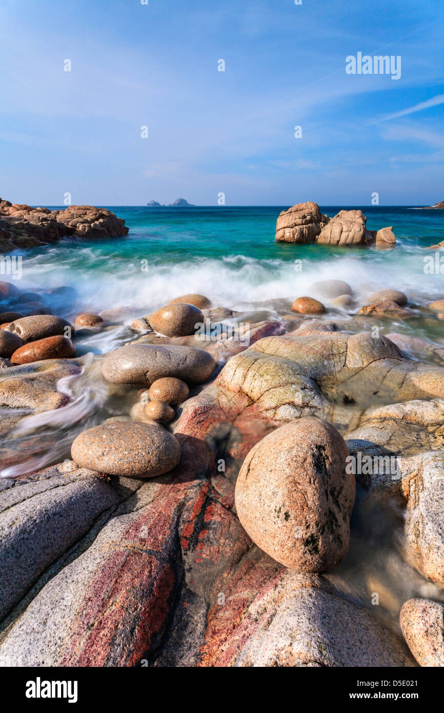 Felsbrocken auf Porth Nanven Bucht mit Bubble Gum Rock und The Brisons in der Ferne. Stockfoto