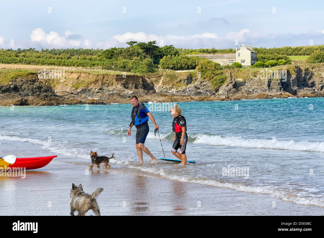 Reifer Mann und Frau mit einem Kanu und zwei Hunden, Harlyn Bay, Cornwall, England Stockfoto