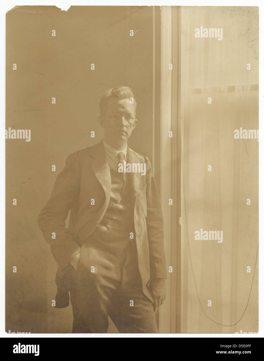 Ein Vintage-Porträt des amerikanischen Künstlers Charles Sheeler, aufgenommen von Peter A. Juley & Son im Jahr 1910. Das Foto zeigt Sheeler, der an einem Fenster steht, mit der Hand in der Tasche, eine typische Pose für Künstlerporträts des frühen 20. Jahrhunderts. Stockfoto