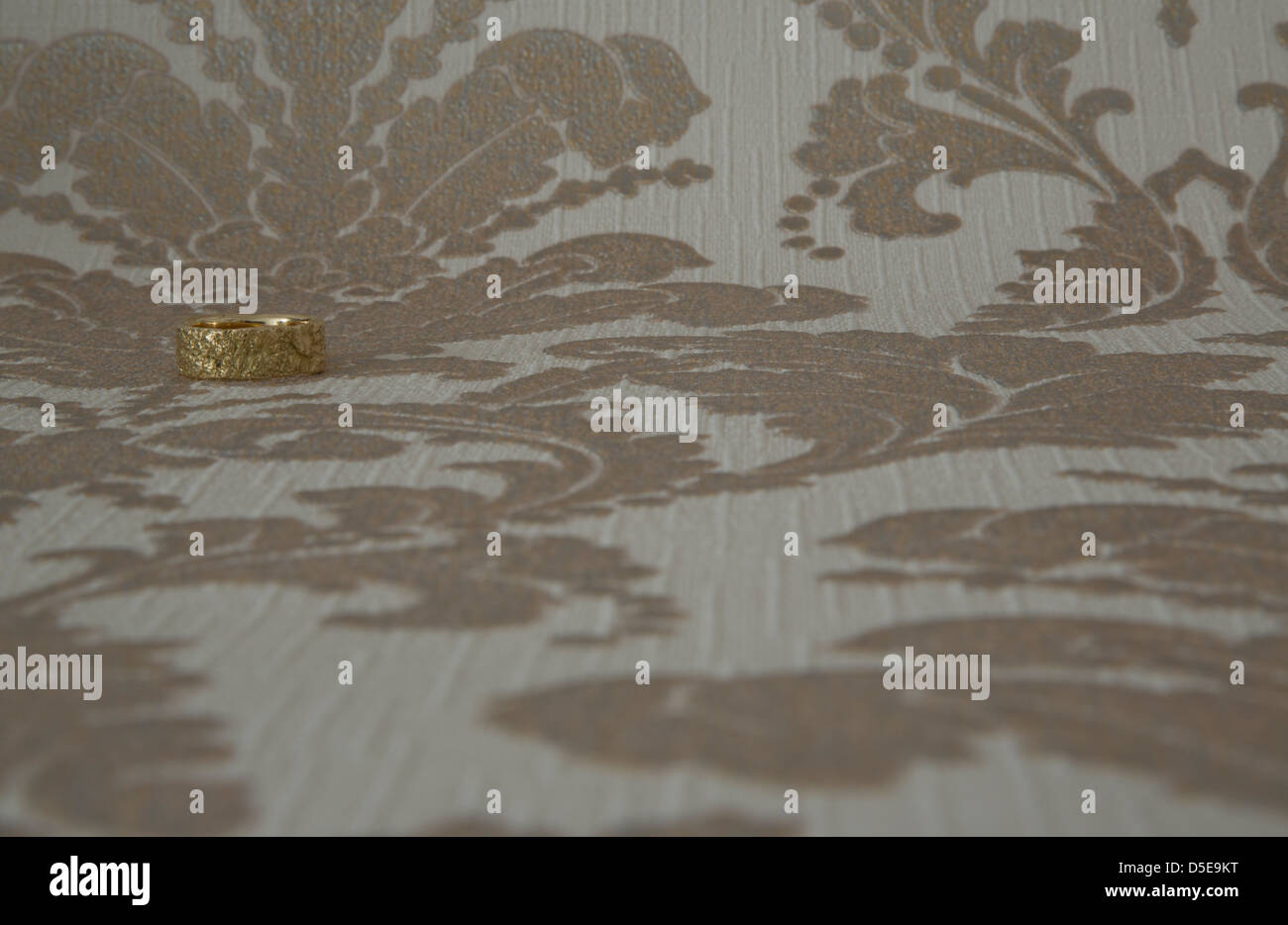 Einen goldenen Ehering vor einer Tapete. März 2013 Stockfoto