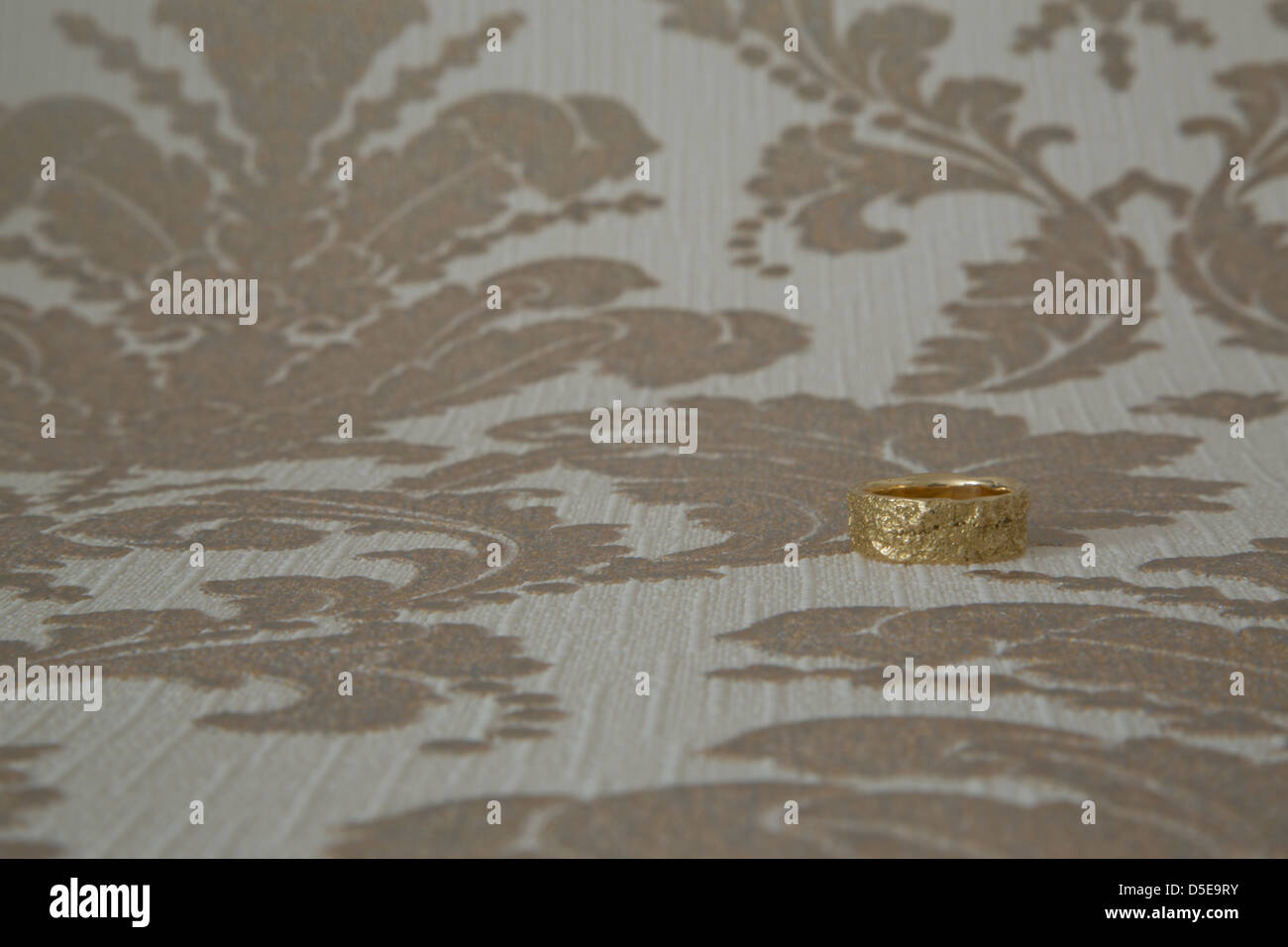 Einen goldenen Ehering vor einer Tapete. März 2013 Stockfoto