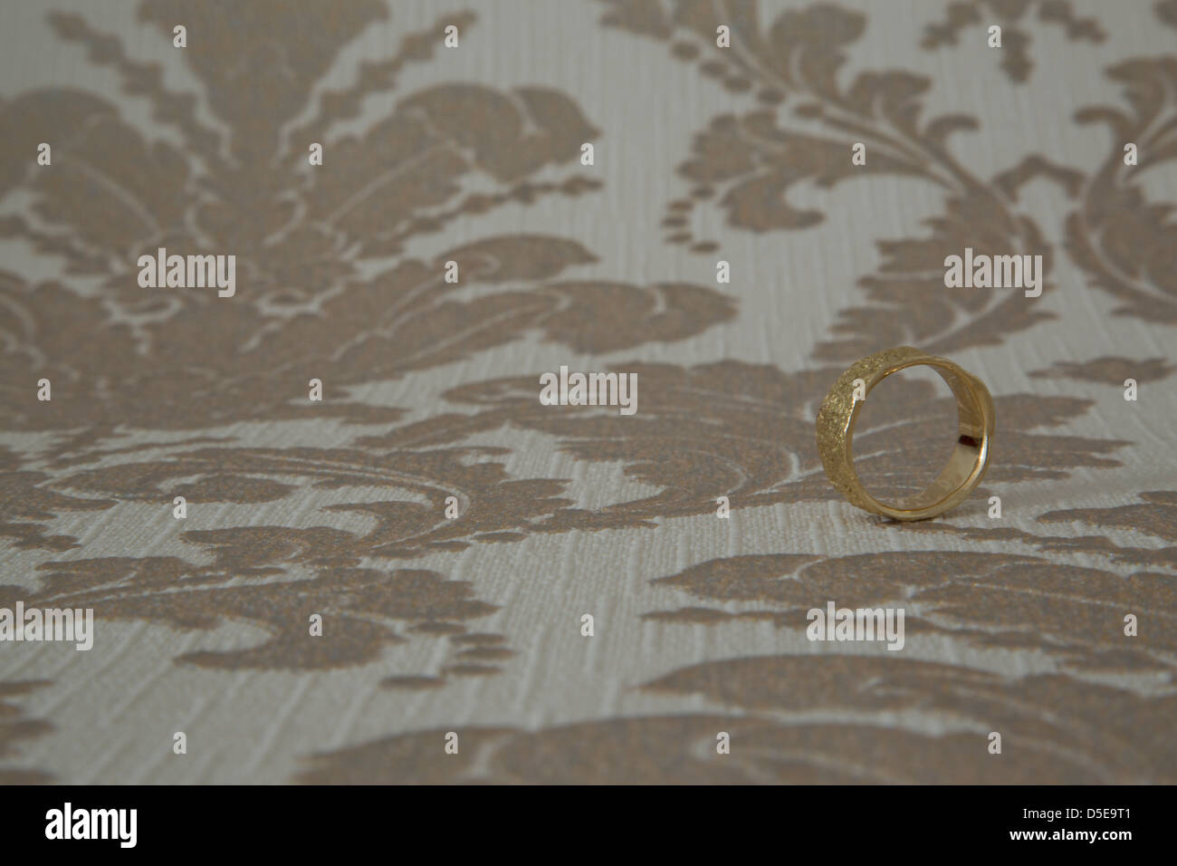 Einen goldenen Ehering vor einer Tapete. März 2013 Stockfoto