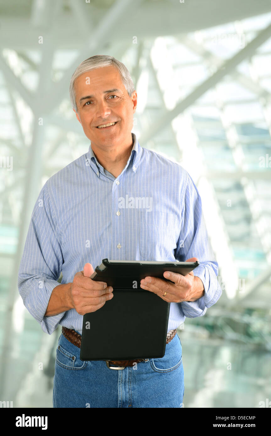 Nahaufnahme eines lässig Geschäftsmann in einer modernen Fabrik Einstellung hält einen Tabletcomputer. Hochformat. Stockfoto