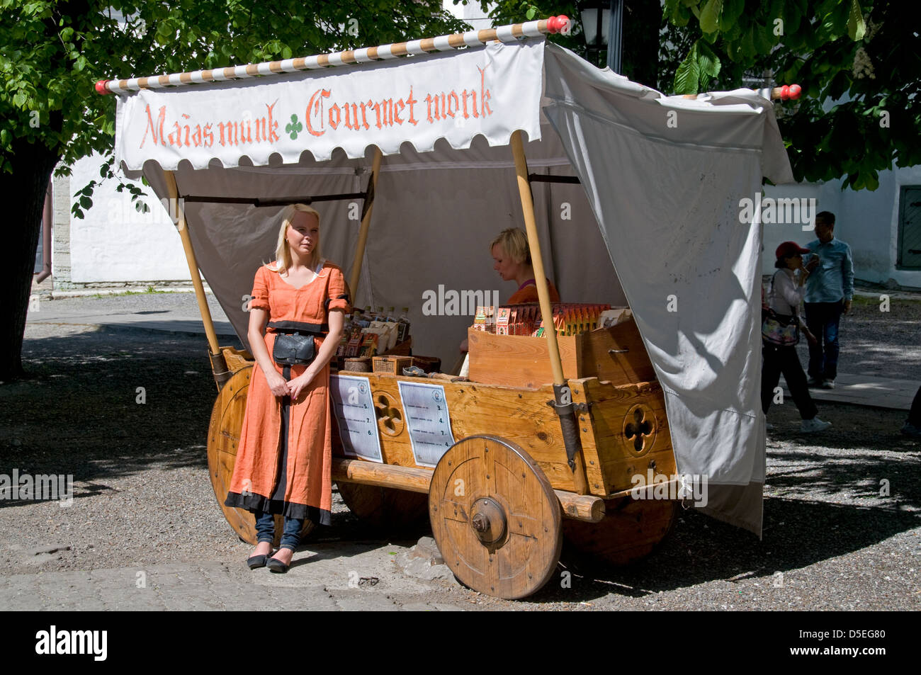 Ein junges Mädchen in mittelalterlicher Tracht als Gourmet-Mönch wartet auf Kunden, Tallinn klebrige kaufen kandierten Mandeln. Stockfoto
