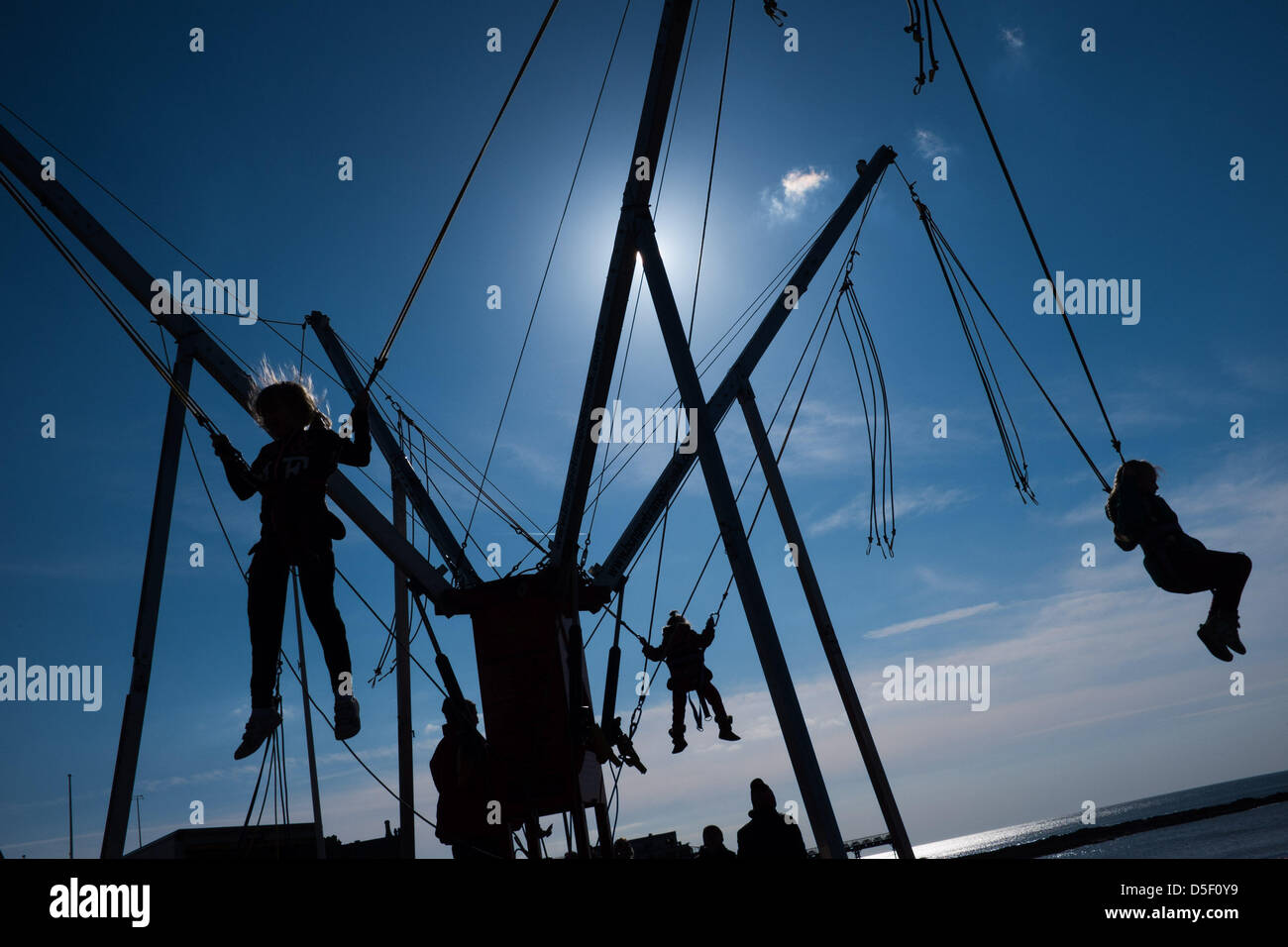 Aberystwyth Wales UK, Ostern Sonntag, 31. März 2013. Kinder freuen sich über die Frühlingssonne auf die Bunjee-Trampolin auf Aberystwyth Promenade zu spielen. Anhaltende östlich windet Mittel, das dies der kälteste März 1962 wurde, und Temperaturen werden eingestellt, um unter dem Durchschnitt für die erste Woche im April Foto © Keith Morris Stockfoto