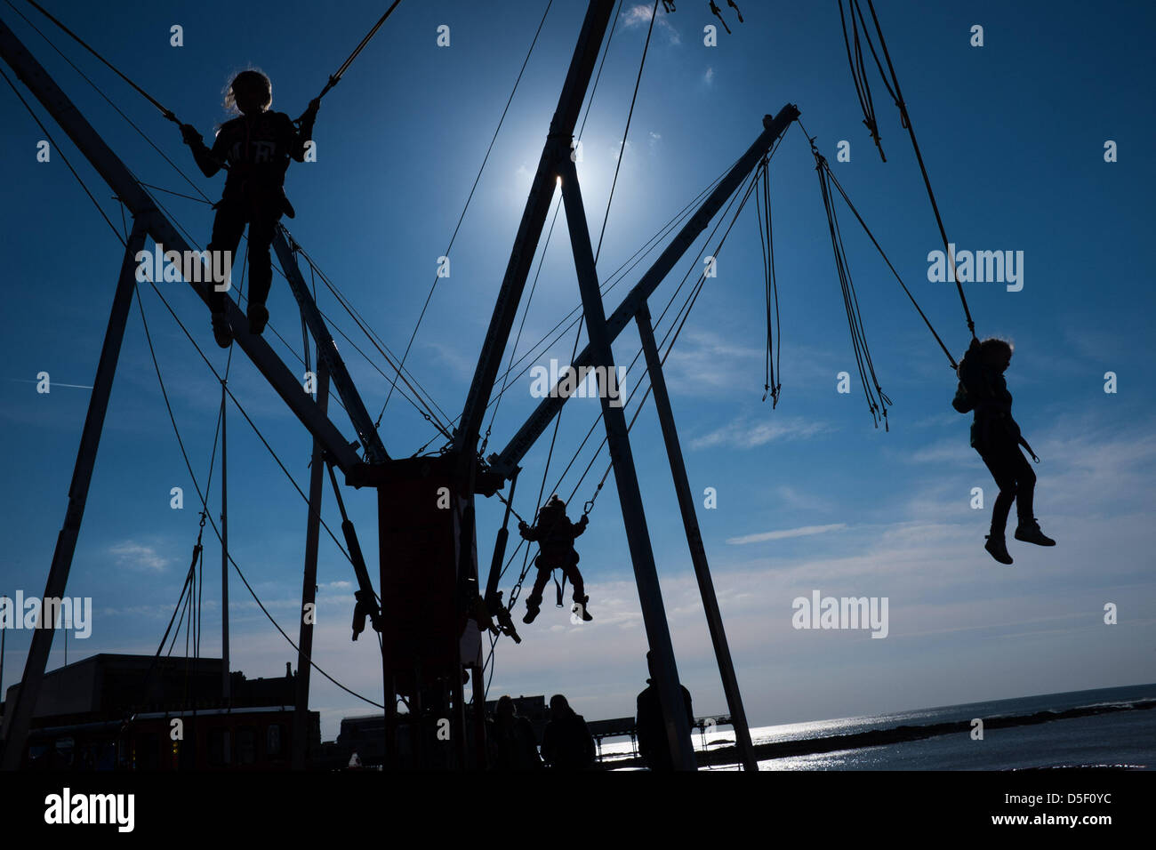 Aberystwyth Wales UK, Ostern Sonntag, 31. März 2013. Kinder freuen sich über die Frühlingssonne auf die Bunjee-Trampolin auf Aberystwyth Promenade zu spielen. Anhaltende östlich windet Mittel, das dies der kälteste März 1962 wurde, und Temperaturen werden eingestellt, um unter dem Durchschnitt für die erste Woche im April Foto © Keith Morris Stockfoto