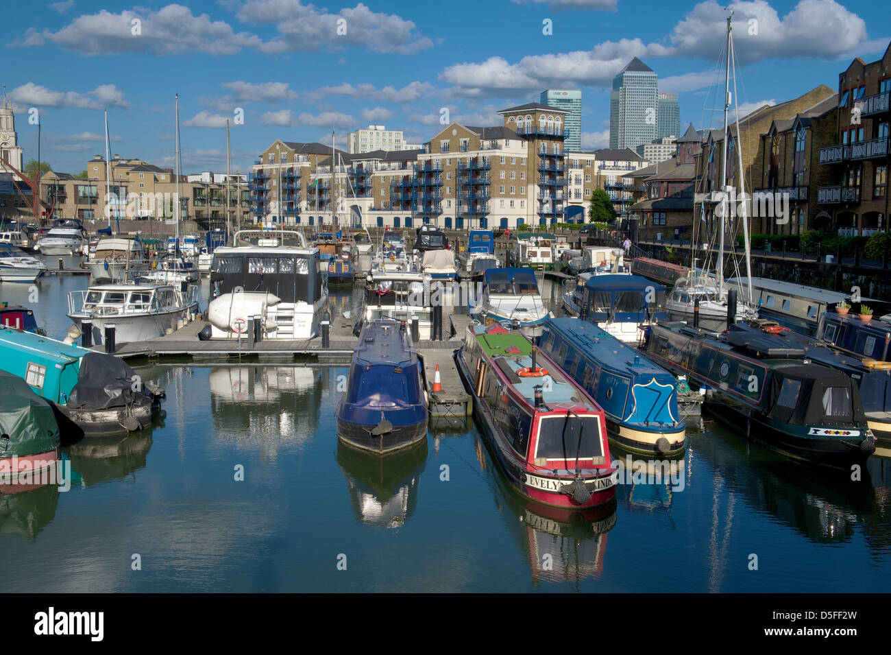 Schmale Boote ankern in Limehouse Bassin mit Wohnungen und Canary Wharf in den Hintergrund, London, UK Stockfoto