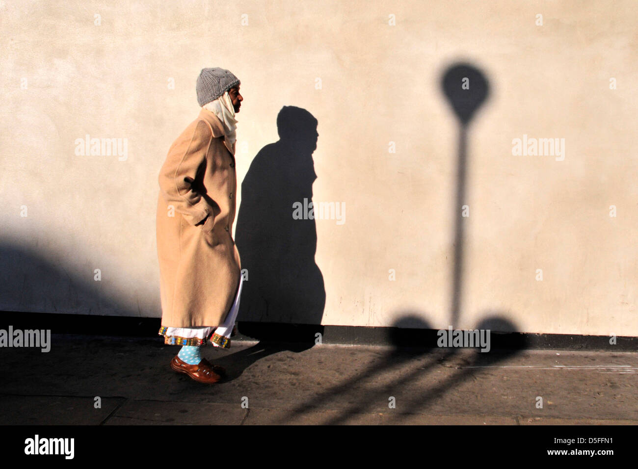 Eine alte Frau geht an einem sonnigen Tag in Goldborne Road, West London, Vereinigtes Königreich Stockfoto