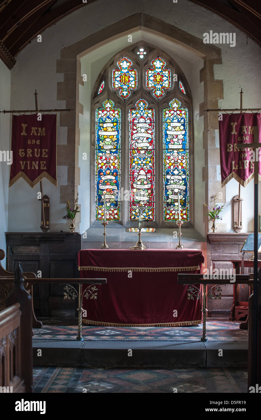 Altar der Kirche mit Morgenlicht durch die Buntglasfenster in der historischen Kirche St. Mary De Malmsbury, Littleton Stockfoto