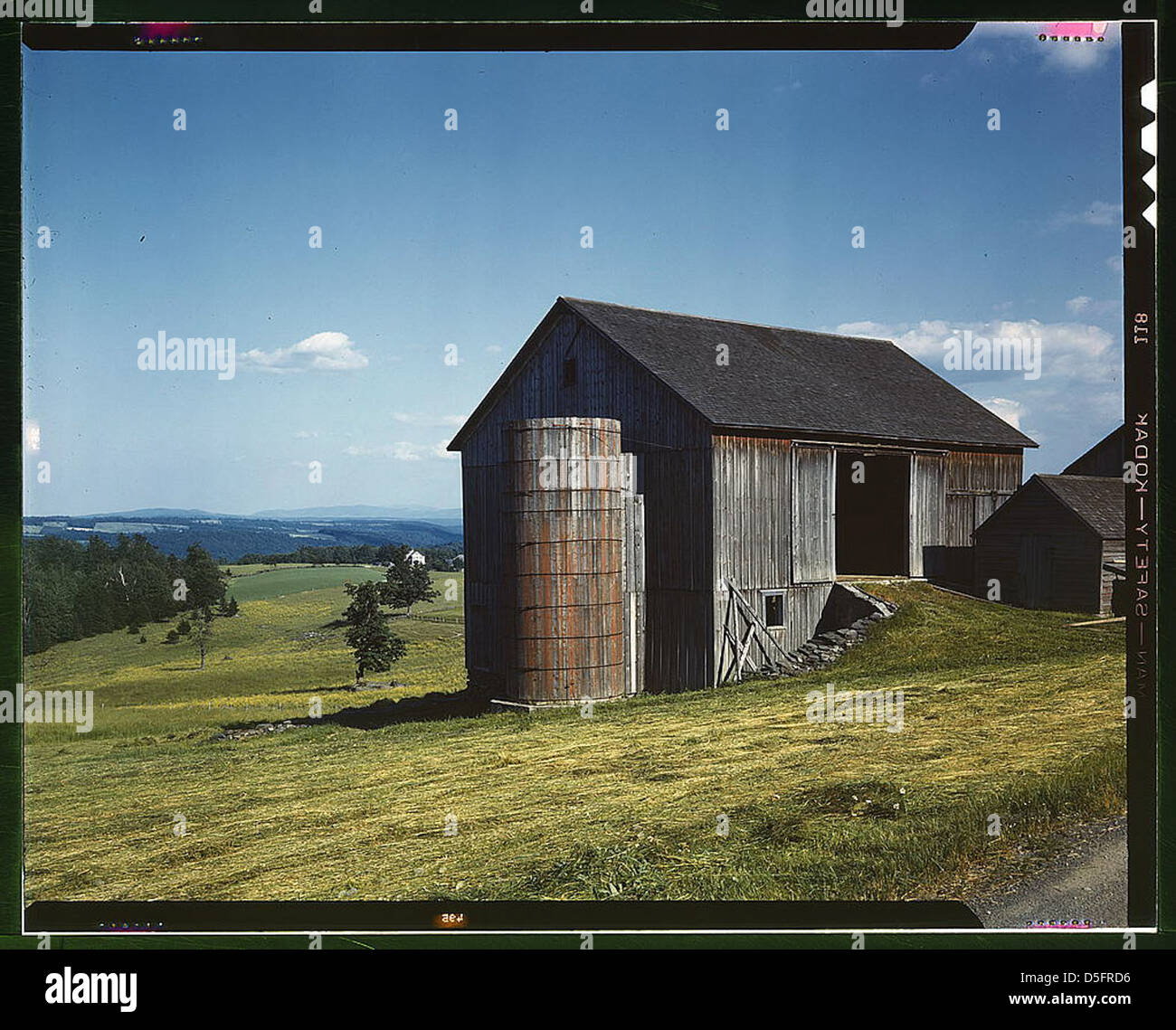Dieses Foto aus den 1940er Jahren zeigt Ackerland in der Catskill-Region des Bundesstaates New York und zeigt eine ländliche Landschaft. Das Bild zeigt eine grüne Weide, eine verwitterte Holzscheune und sanfte Hügel unter blauem Himmel, die das ländliche landwirtschaftliche Leben im Hinterland von New York während dieser Zeit veranschaulichen. Stockfoto