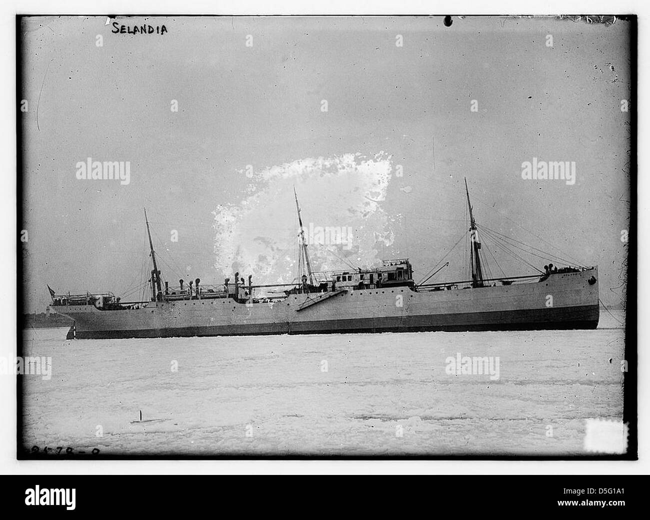 Ein Schwarzweißfoto der Selandia, einem Dieselmotorschiff, das im Wasser vor Anker liegt. Das Bild hebt die Flagge der Ostasiatischen Kompanie hervor und zeigt Rettungsboote und den Schiffsmast. Stockfoto