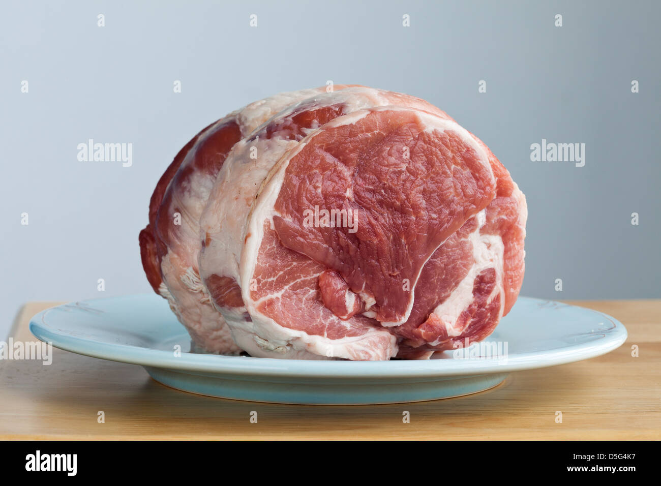 2,5 Pfund rohes Schweinefleisch braten auf einem blauen Teller Stockfoto