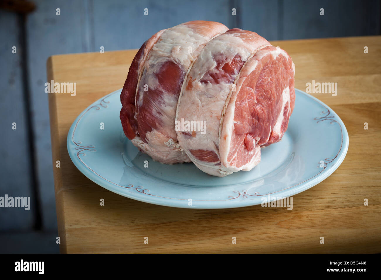 2,5 Pfund rohes Schweinefleisch braten auf einem blauen Teller Stockfoto