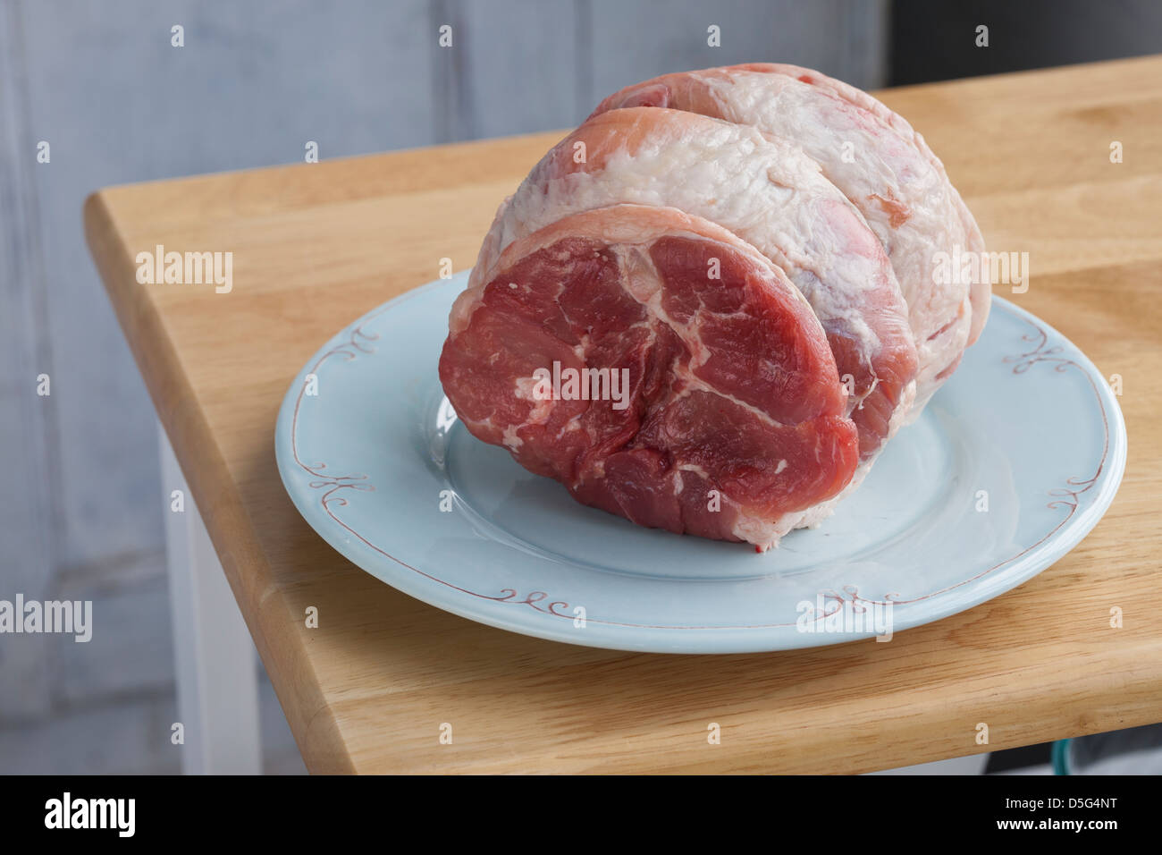 2,5 Pfund rohes Schweinefleisch braten auf einem blauen Teller Stockfoto