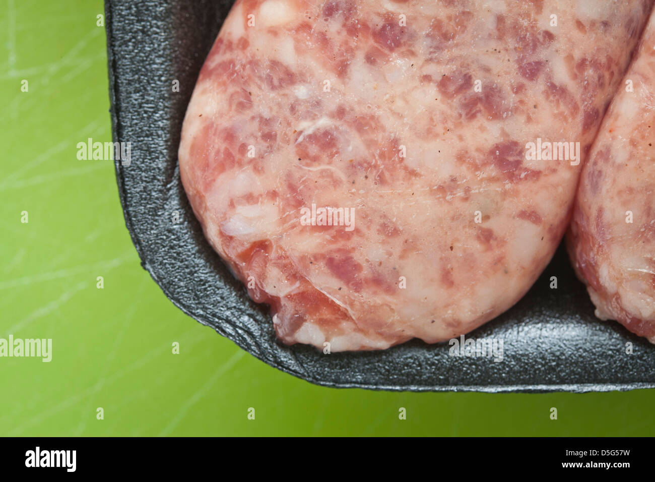 Rohes Fleisch Wurst, Brat, aus schwarzem Kunststoff auf grünem Hintergrund Stockfoto