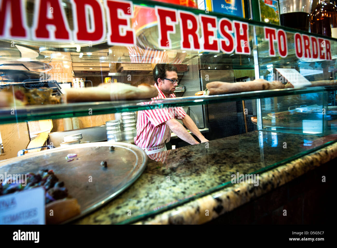 New York Style Pizza Restaurant mit Mann Pizzabacken hinter Glas-Theke Stockfoto