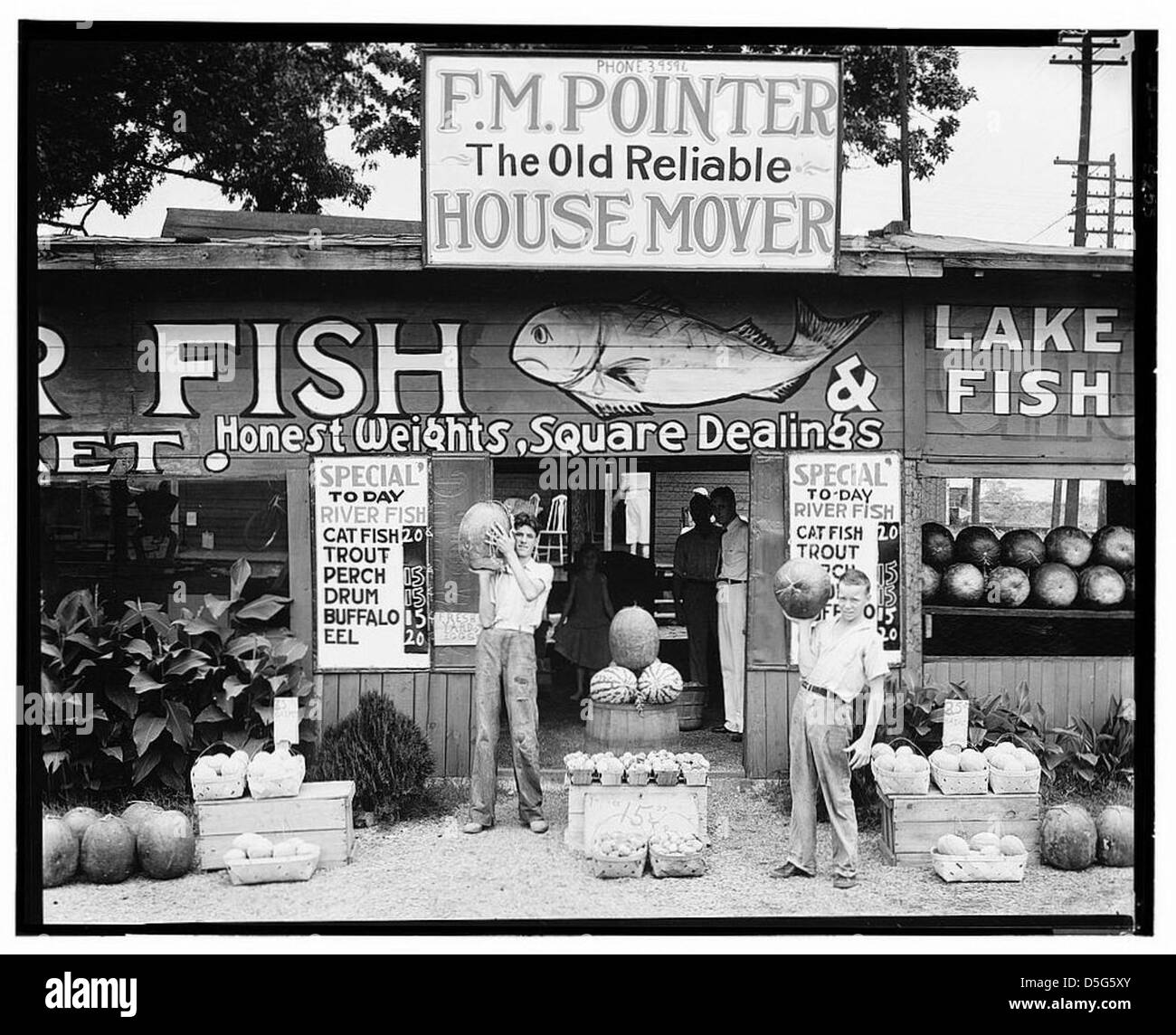 Ein Stand am Straßenrand in der Nähe von Birmingham, Alabama, wurde 1936 gefangen und zeigt lokale Produkte wie Melonen und Fisch. Das Foto spiegelt das ländliche Leben und die wirtschaftlichen Aktivitäten der damaligen Zeit wider. Stockfoto