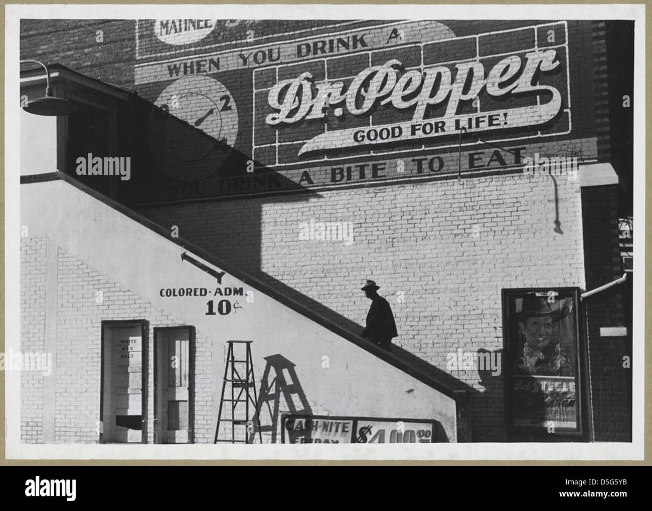 Dieses Foto zeigt einen afroamerikanischen Mann, der in den 1930er Jahren den farbigen Eingang eines Kinos in Belzoni, Mississippi, betritt und die Rassentrennung der Epoche widerspiegelt. Stockfoto