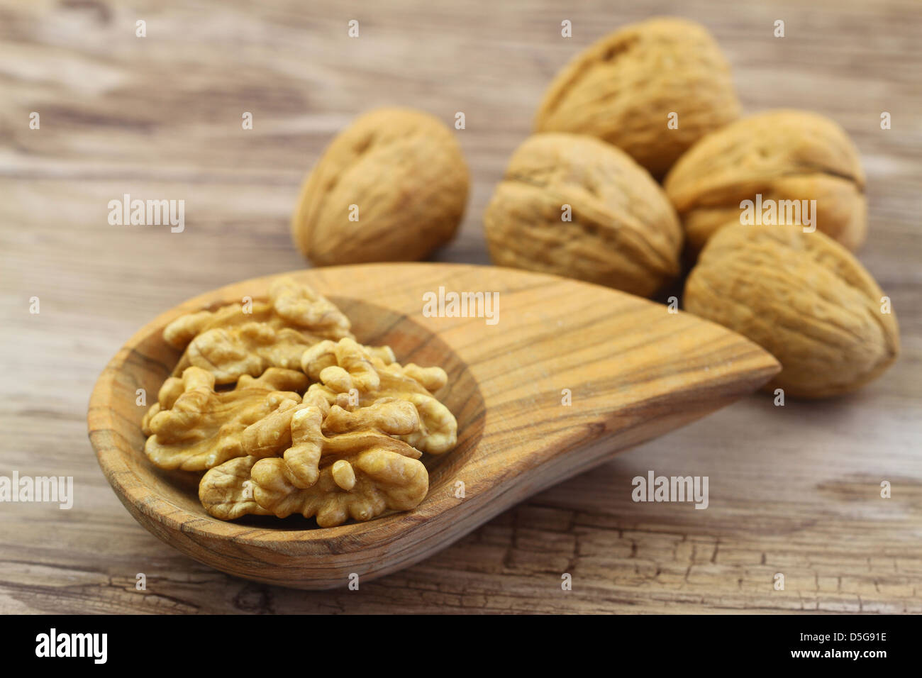 Walnüsse mit und ohne Schale auf hölzernen Hintergrund Stockfoto