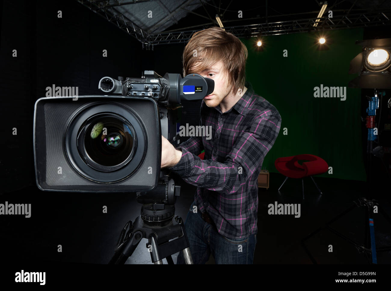 Betreiber sieht in den Sucher ein TV-Studio-Kamera mit Lichtern und CSO grünen Vorhang im Hintergrund. Stockfoto