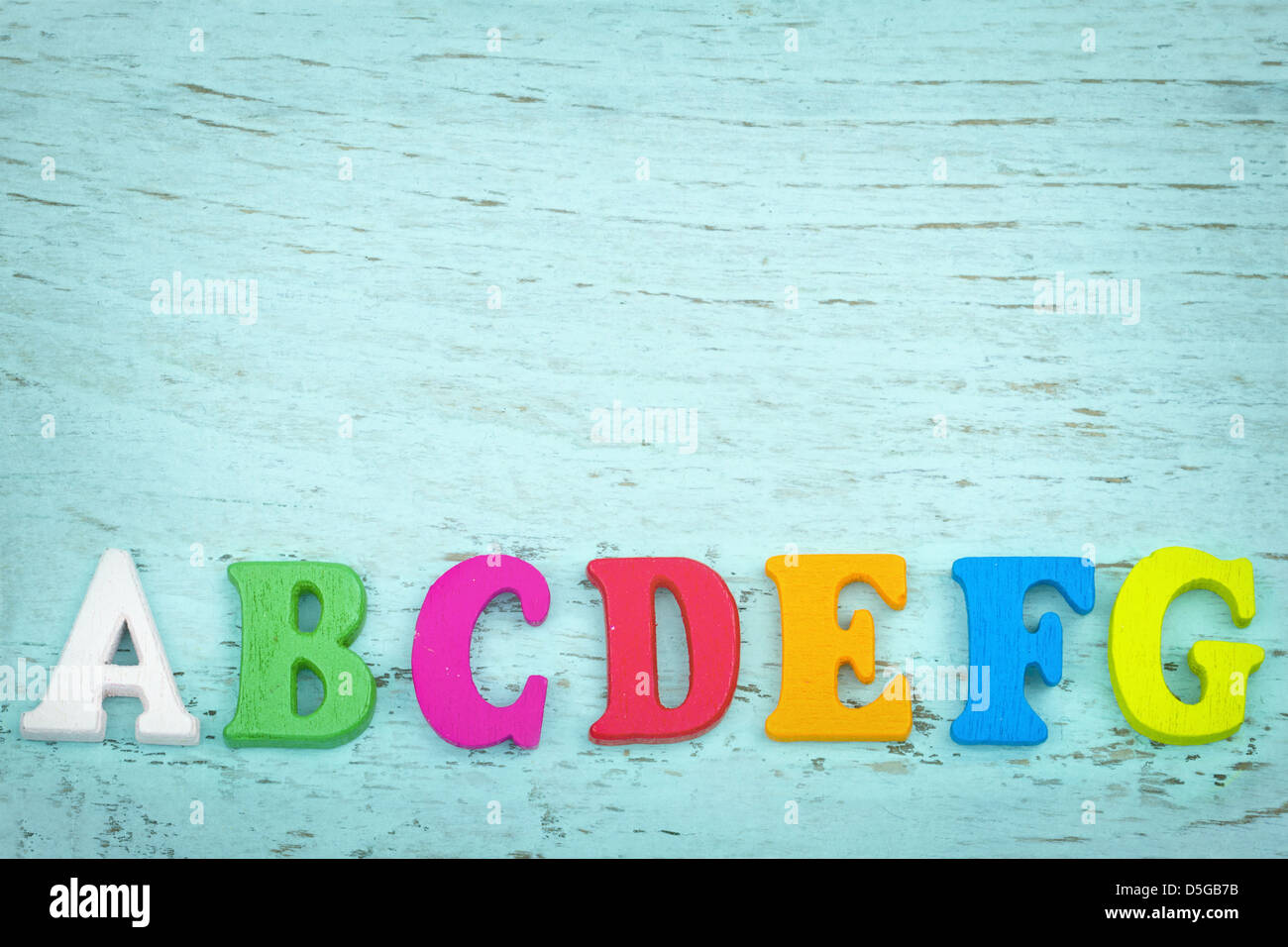 Bunte Buchstaben mit textfreiraum auf hellblauem Hintergrund aus Holz Stockfoto