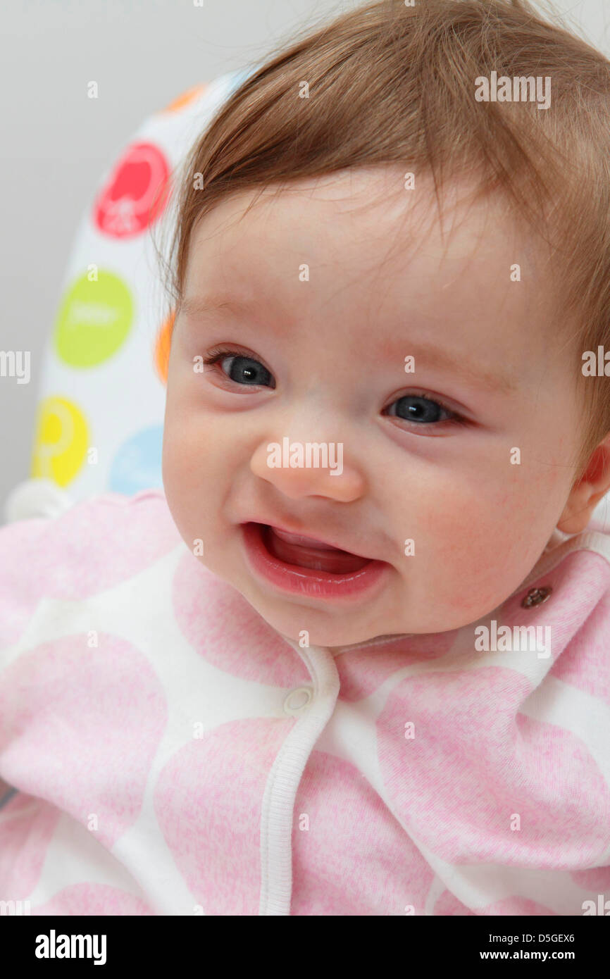 Acht Monate altes Baby Mädchen tragen rosa Strampler in ihrem Hochstuhl auf ihr erstes Ostern abgebildet. Stockfoto