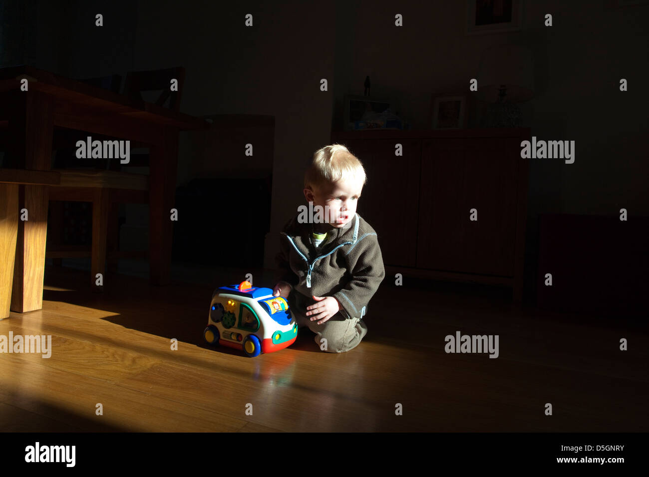 2 Jahre alter Junge spielt in der Abendsonne Licht im Inneren zu Hause, England, UK Stockfoto