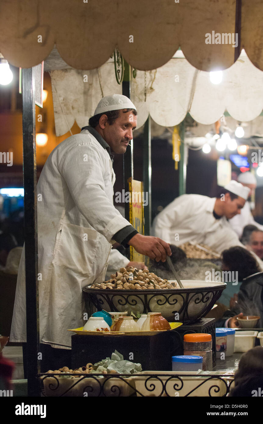 Mann, Verkauf von Schnecken aus einem Stall in dem Djemaa el-Fna-Platz in der Nacht, Marrakesch, Marokko Stockfoto