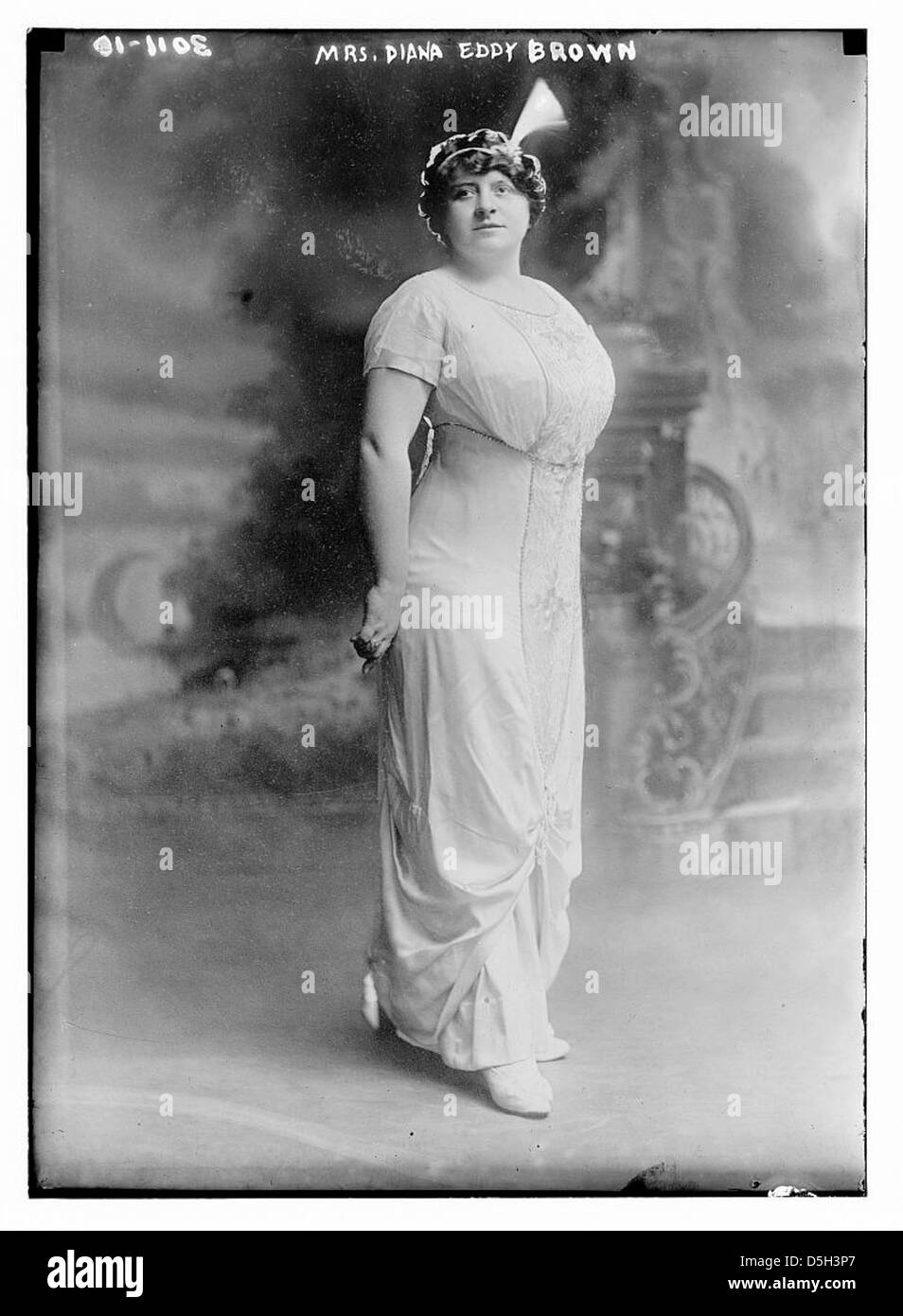 Mrs. Diana Eddy Brown wird in einem formellen Porträt dargestellt, in einem eleganten weißen Kleid, das die Anmut und Ausgeglichenheit verkörpert, die typisch für Frauen aus der Gesellschaft des frühen 20. Jahrhunderts sind. Das Bild spiegelt ihre Rolle im kulturellen und sozialen Leben während ihrer Zeit wider. Stockfoto