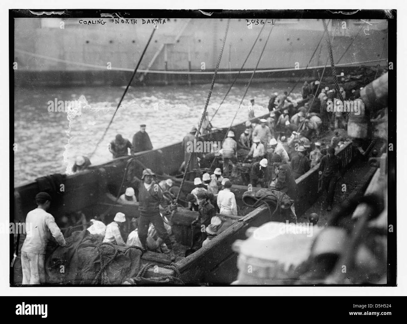 Ein historisches Bild des Kriegsschiffs USS North Dakota (BB-29), das mit Kohle versorgt wurde, zeigt seine Rolle während der Marineoperationen des frühen 20. Jahrhunderts. Stockfoto