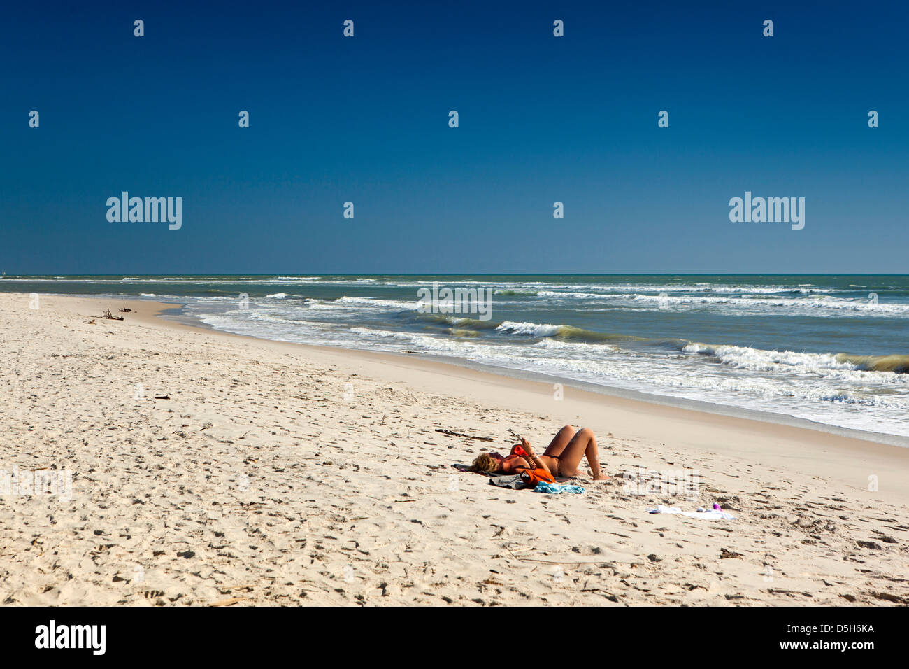 Madagaskar, Morondava, Strand, einsame weibliche Touristen Sonnenbaden am leeren Strand Stockfoto