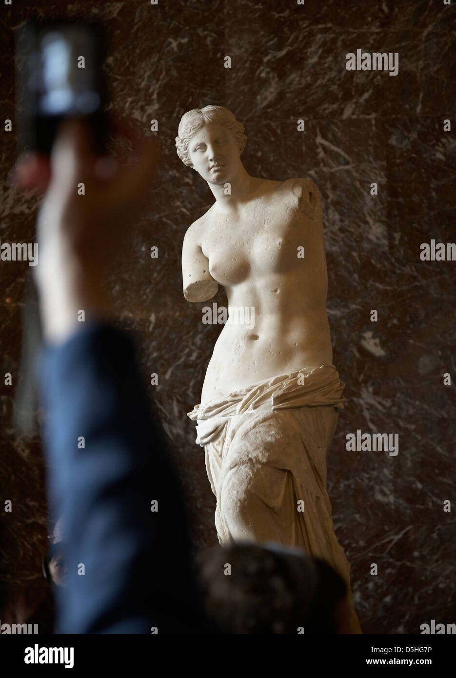 Venus von Milo, Aphrodite-Statue im Louvre mit einem touristischen Arm und Hand mit dem Fotografieren Stockfoto