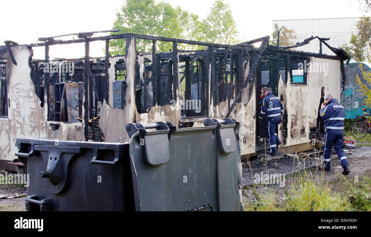 HANDOUT - geben Sie Polizisten einen ausgebrannten Asyl suchender Schutz in Ellhofen, Deutschland, 19. September 2012. Das Feuer kam in der Nacht vom 18. zum 19. September 2012. 17 Personen wurden in der hölzernen Baracke untergebracht. Sie wurden in ein anderes Tierheim verschoben. Sechs Asylbewerber und zwei Feuerwehrleute wurden leicht verletzt. Das Feuer verursachte Schäden von 100.000 Euro. Foto: FEUERWEHR ELLHOFEN Stockfoto