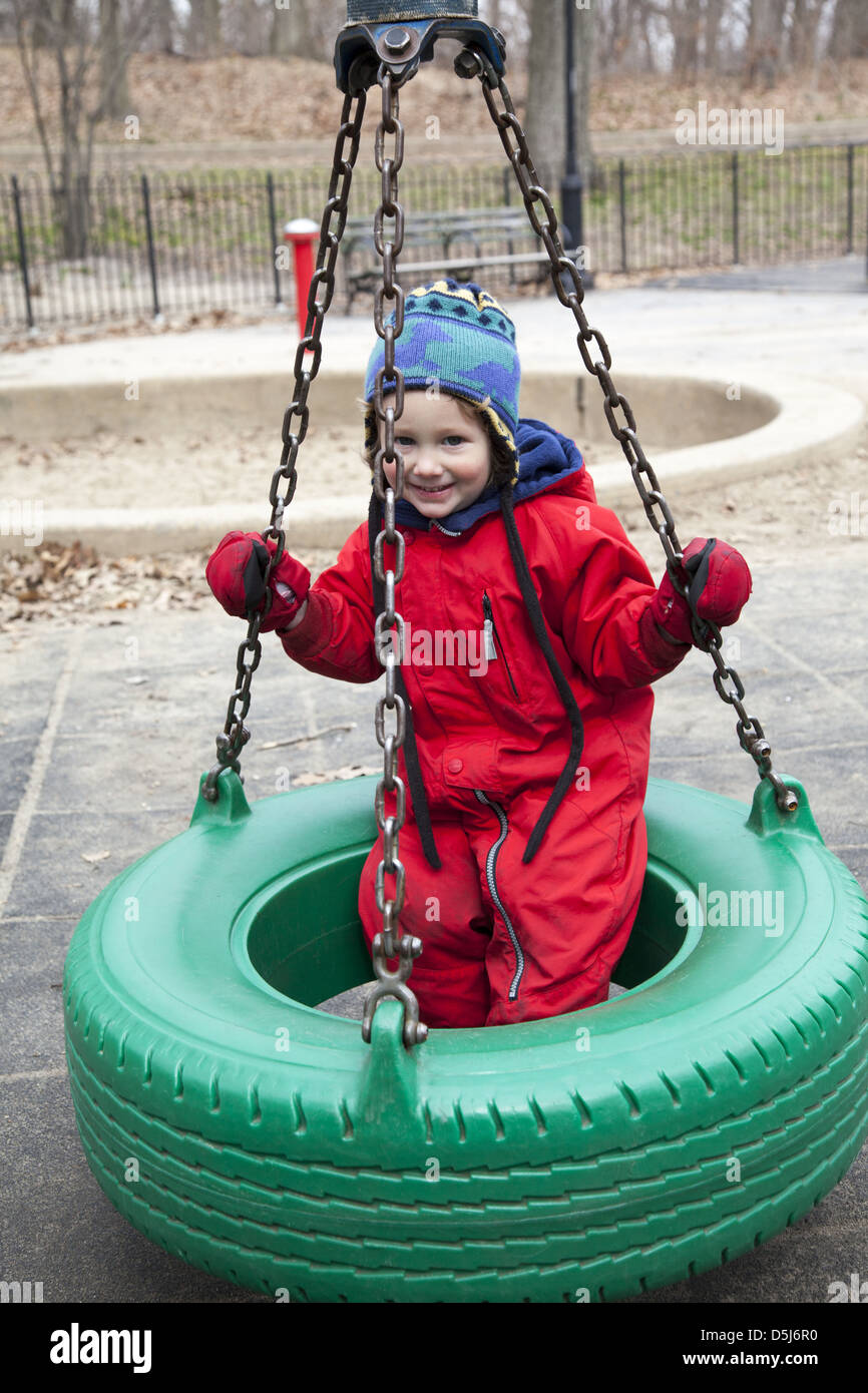 Kleiner Junge glücklich auf den Reifen schwingen auf dem 3. Platz St.-Spielplatz im Prospect Park, Brooklyn, NY. Stockfoto