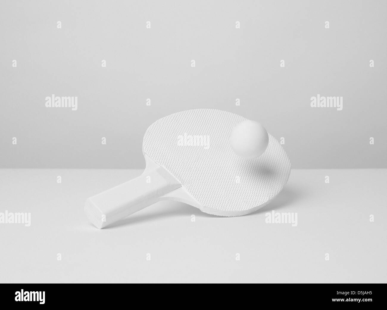 Ein Ping-Pong-Schläger und Ball sitzen auf einem sauberen weißen Tisch Stockfoto