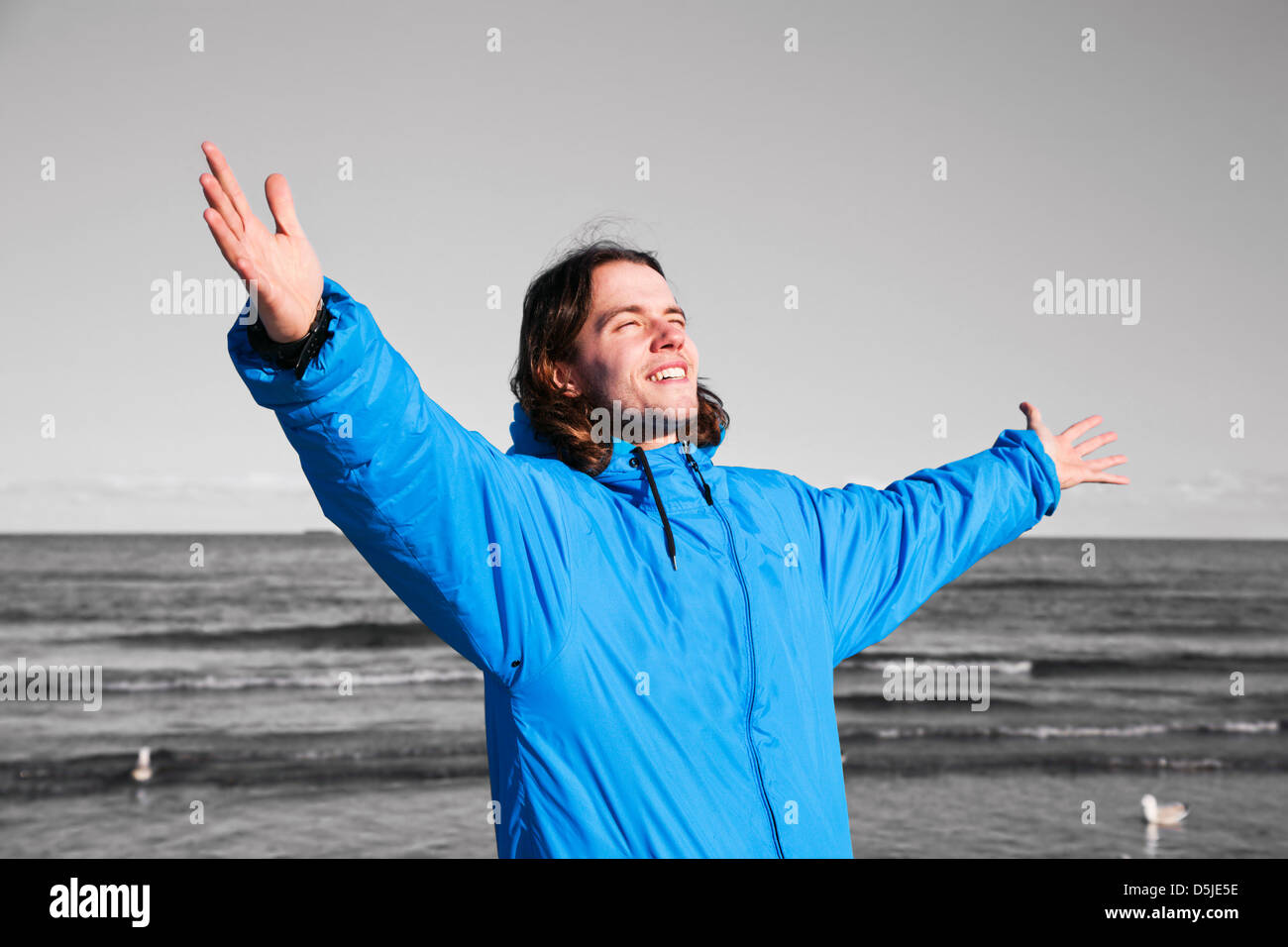 Glücklicher Mann am Strand mit Händen stehend auf schwarzen und weißen Seenlandschaft. Konzepte wie die Überwindung der Depression etc.. Stockfoto
