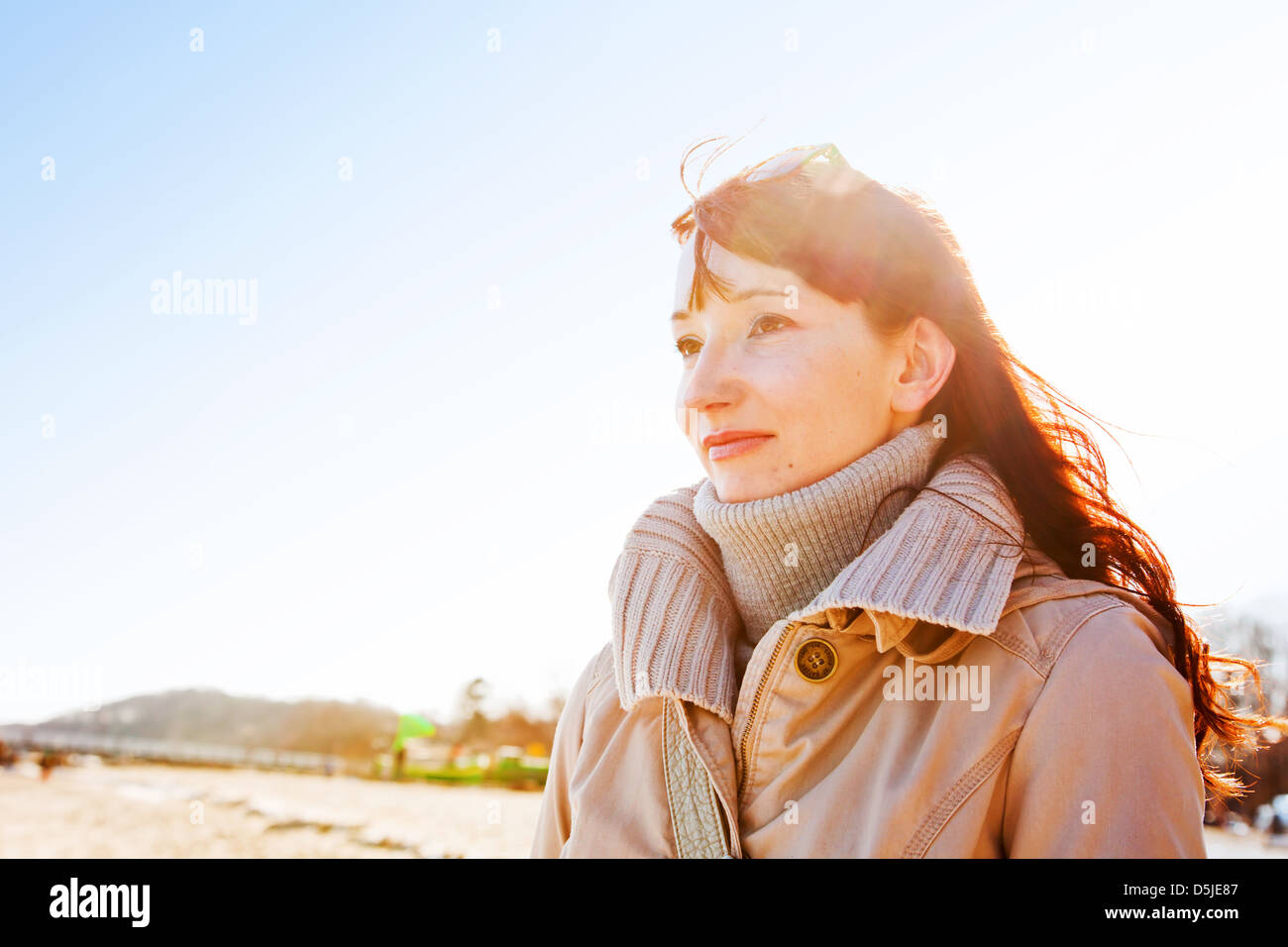 Junge Frau draußen in der Wintersonne an der Küste Stockfoto