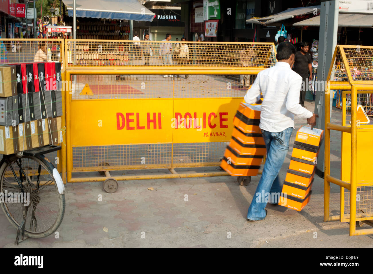 Ein Mann trägt Schuhkartons durch einen Delhi Polizei Checkpoint und in einem Markt am Vasant Vihar, New Delhi, Indien. Stockfoto