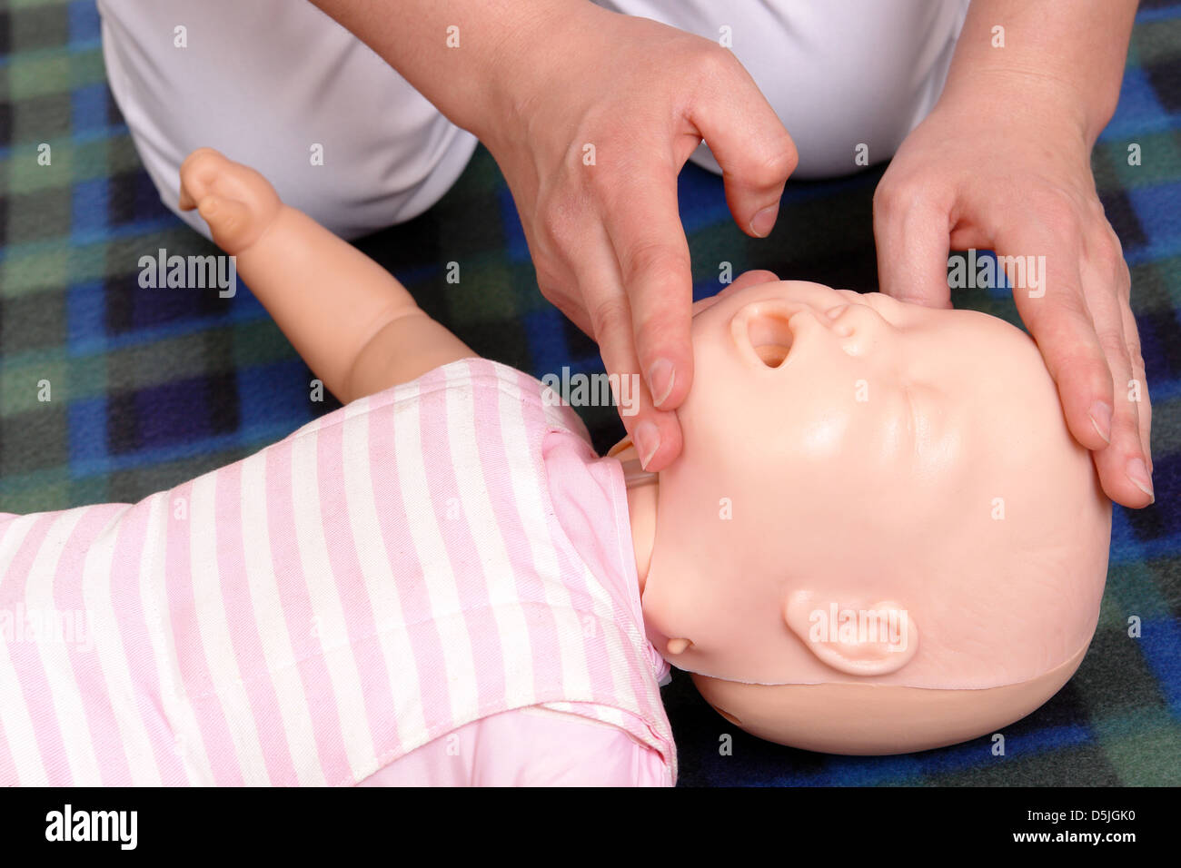 Erste-Hilfe-Ausbilder, die zeigt, wie man Kleinkind Kopf bevor Sie fortfahren zu Mund Beatmung zu positionieren Stockfoto