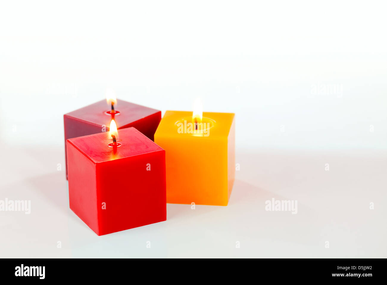 Drei brennende Kerzen vor weißem Hintergrund Stockfoto