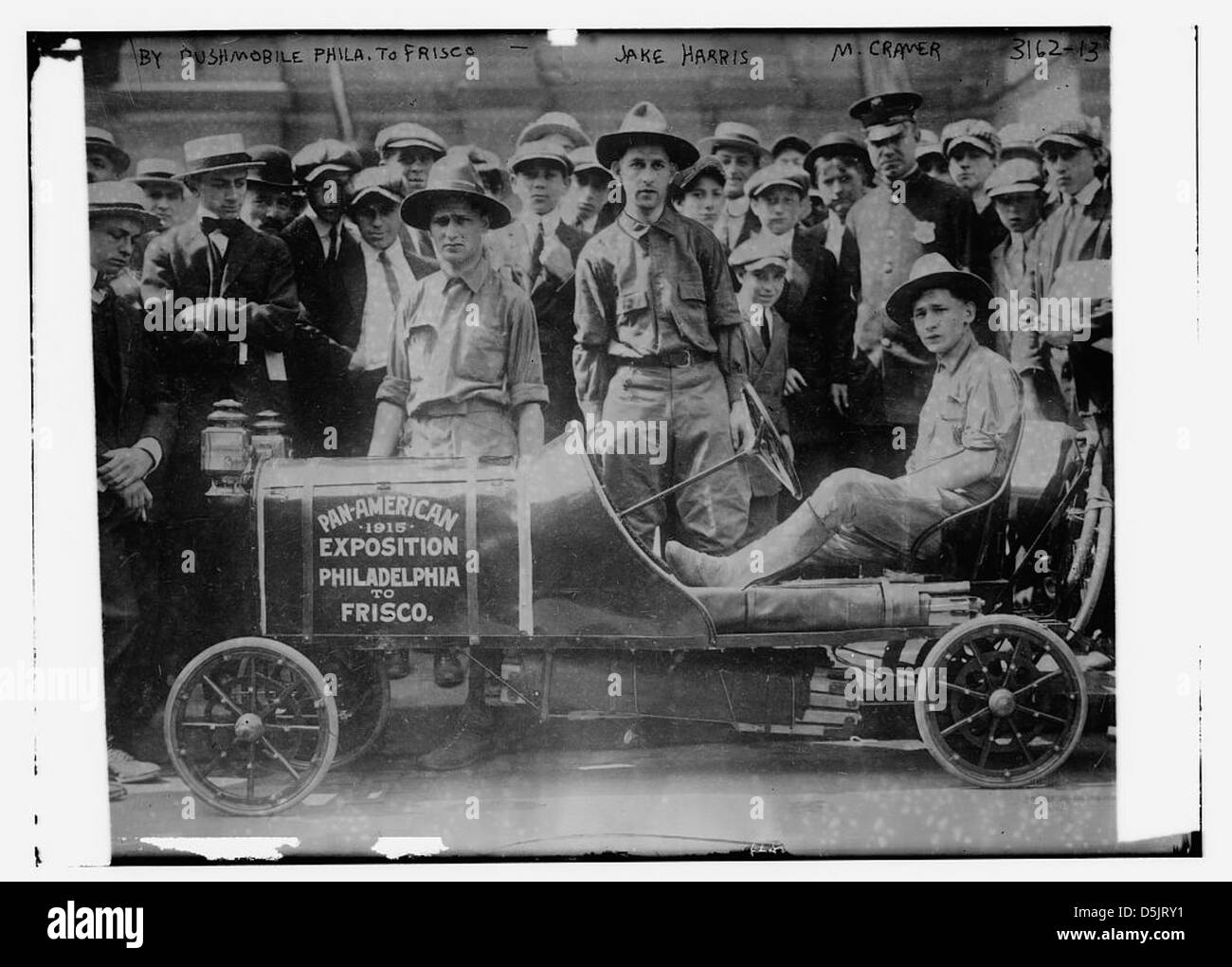 Dieses Bild zeigt Jake Harris und M. Cramer zusammen mit einer Menge Zuschauer, die mit einem Pushmobil von Philadelphia nach San Francisco einen Stunt machen. Die Veranstaltung war Teil der Pan-American Exposition. Stockfoto