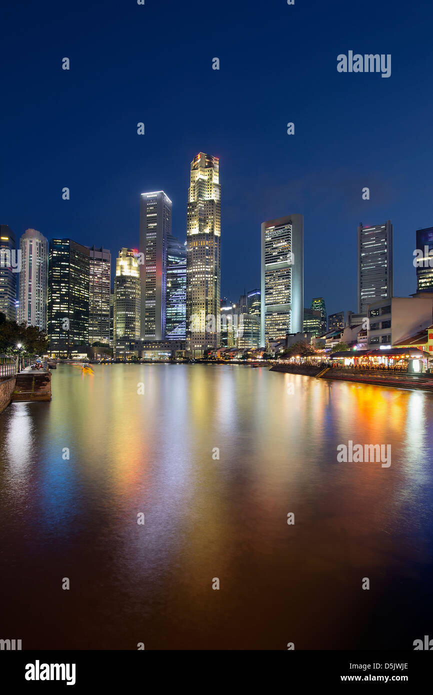 Skyline von Singapur Central Business District (CBD) von Boat Quay am Singapore River bei blaue Stunde senkrecht Stockfoto