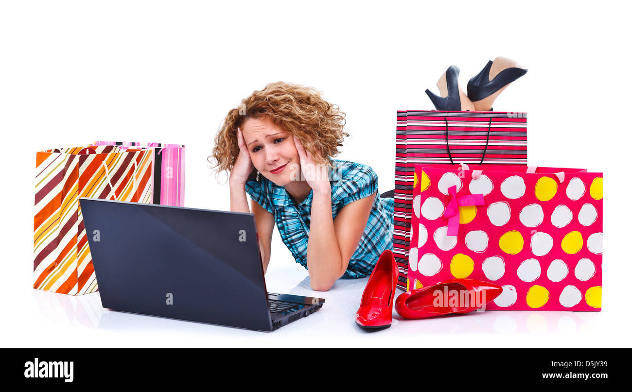 Junge erschöpft Frau liegt auf dem Boden vor Laptop und Einkaufstaschen isoliert auf weißem Hintergrund Stockfoto
