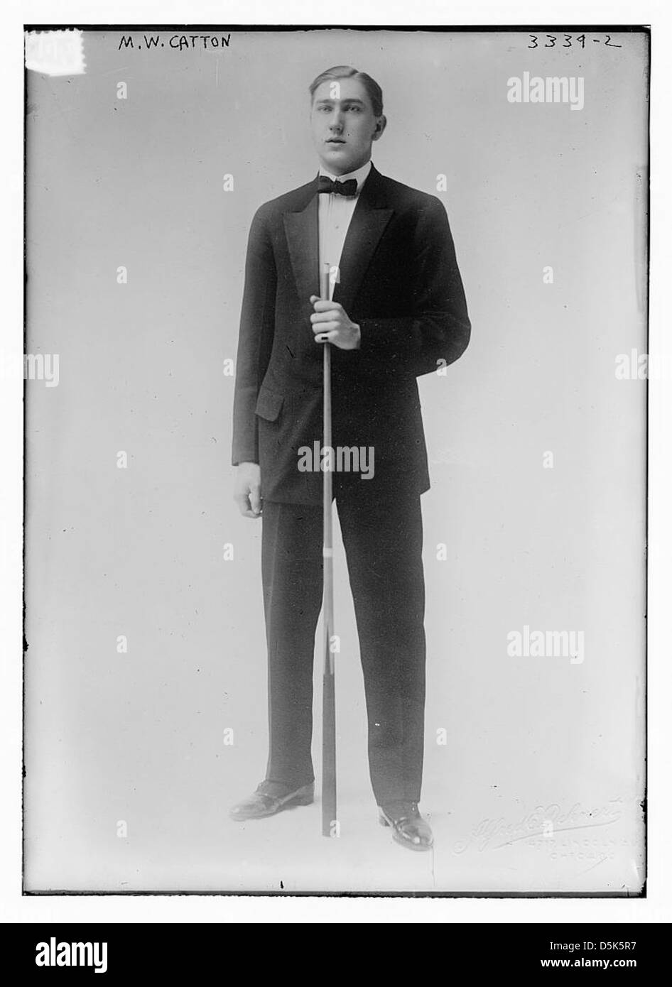 Ein Porträt von Marc W. Catton, einem Fotografen aus Illinois, aufgenommen von Alfred E. Dehnert. Das Bild erfasst das Motiv mit einem Stichstock, der in einen Smoking gekleidet ist und Billard als Thema betont. Stockfoto