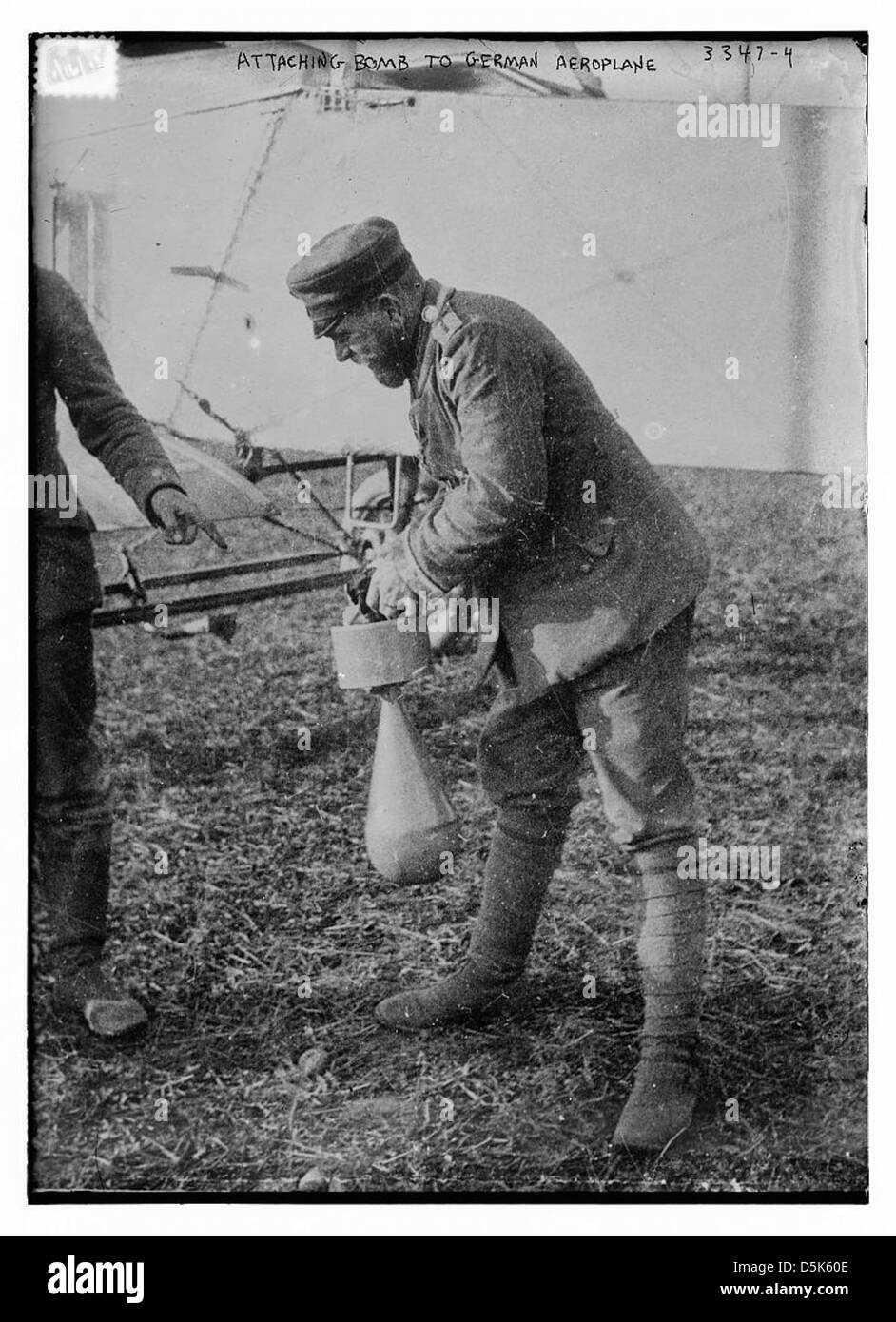 Dieses Bild zeigt den Prozess des Anbringens einer Bombe an einem deutschen Flugzeug während des Ersten Weltkriegs. Luftangriffe waren eine bedeutende Entwicklung in der militärischen Luftfahrt, wobei Bomben eingesetzt wurden, um feindliche Positionen aus der Luft zu zielen. Stockfoto