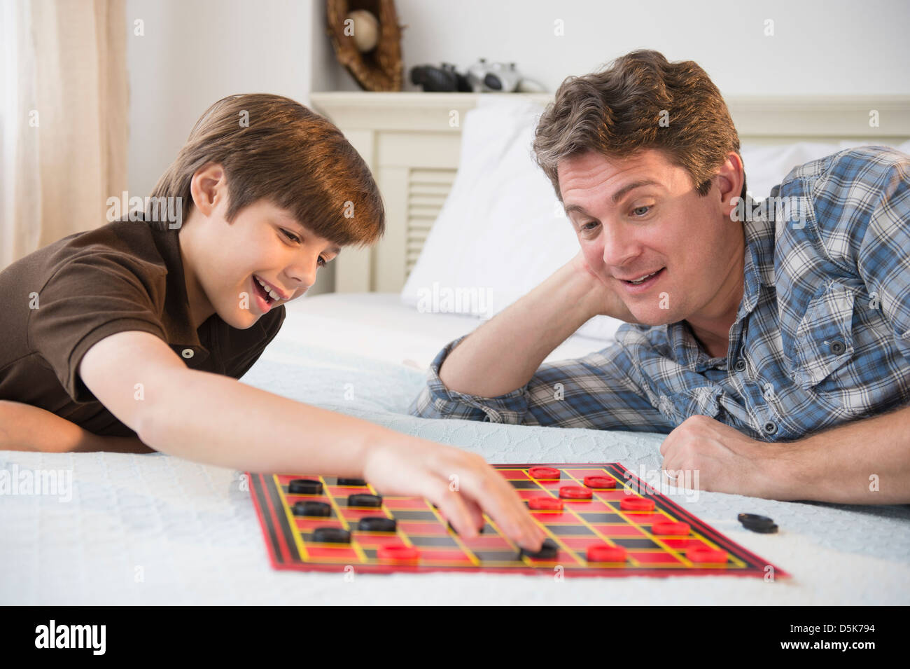 Vater und Sohn spielen Dame (8-9) Stockfoto