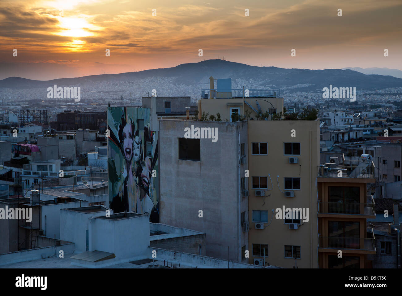 Städtischen Sonnenuntergang: Athen und die umliegenden Hügel. Das Fresko im Vordergrund ist an einem Gebäude im Stadtteil Psirri. Stockfoto